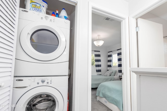 laundry area with stacked washer and clothes dryer and carpet