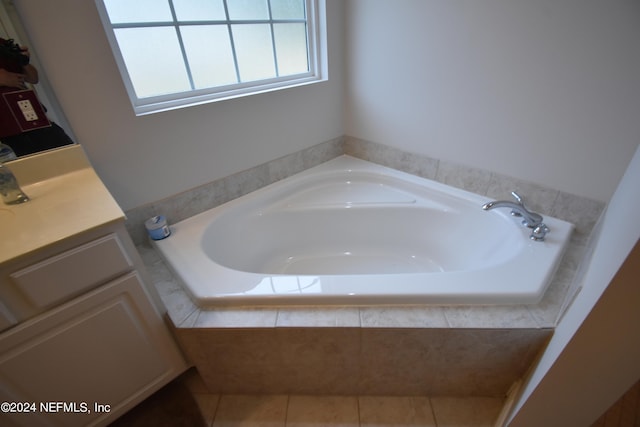 bathroom with tiled tub, vanity, and tile patterned flooring