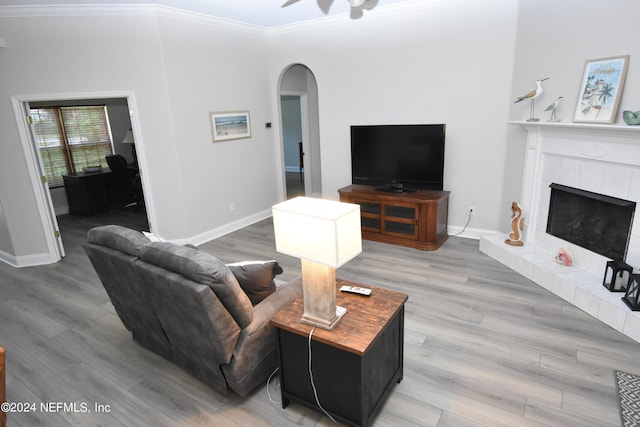 living room with crown molding, a fireplace, hardwood / wood-style floors, and ceiling fan