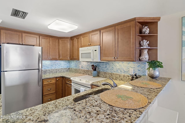 kitchen with kitchen peninsula, white appliances, light stone counters, and backsplash