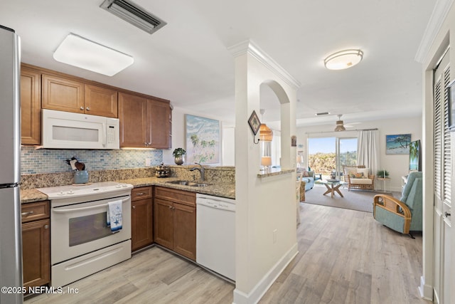 kitchen with sink, light stone counters, light hardwood / wood-style floors, white appliances, and decorative backsplash