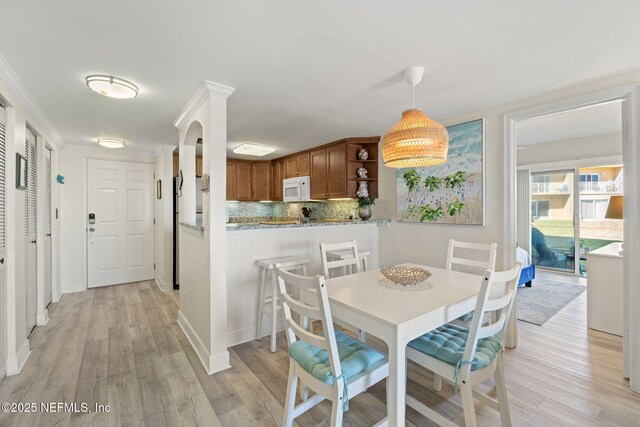 dining space with light wood-type flooring and crown molding