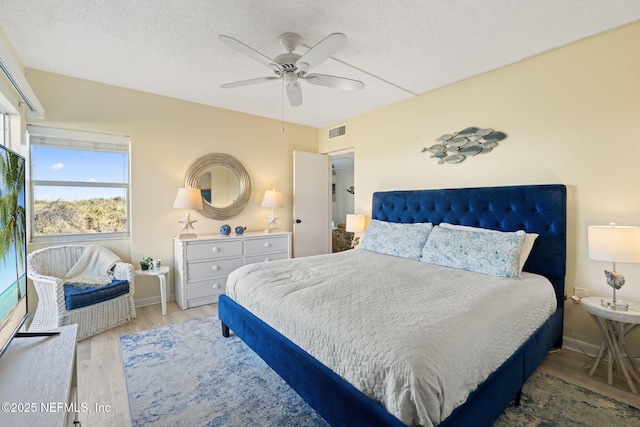 bedroom with hardwood / wood-style flooring, ceiling fan, and a textured ceiling