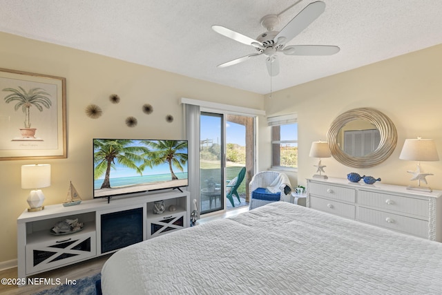 bedroom featuring access to exterior, a textured ceiling, hardwood / wood-style flooring, and ceiling fan