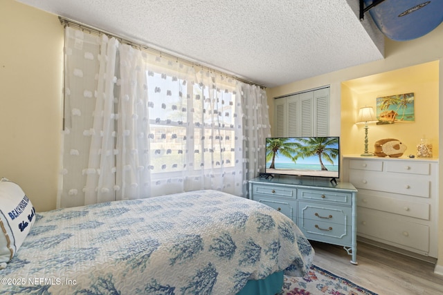 bedroom with a closet, light hardwood / wood-style floors, and a textured ceiling