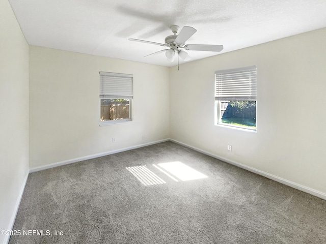 empty room with carpet flooring, ceiling fan, a textured ceiling, and baseboards