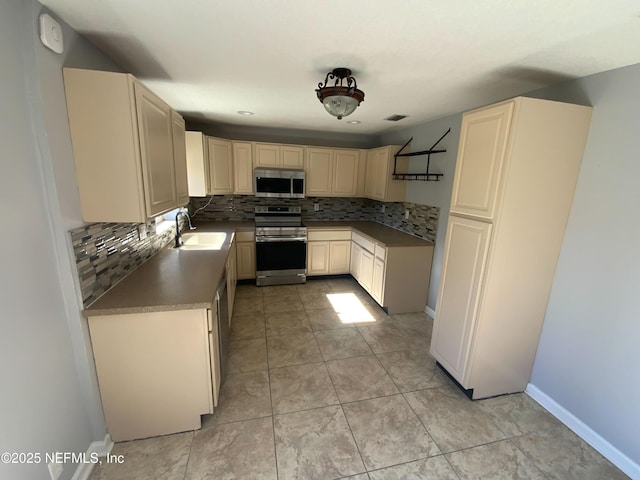 kitchen featuring baseboards, appliances with stainless steel finishes, backsplash, and a sink