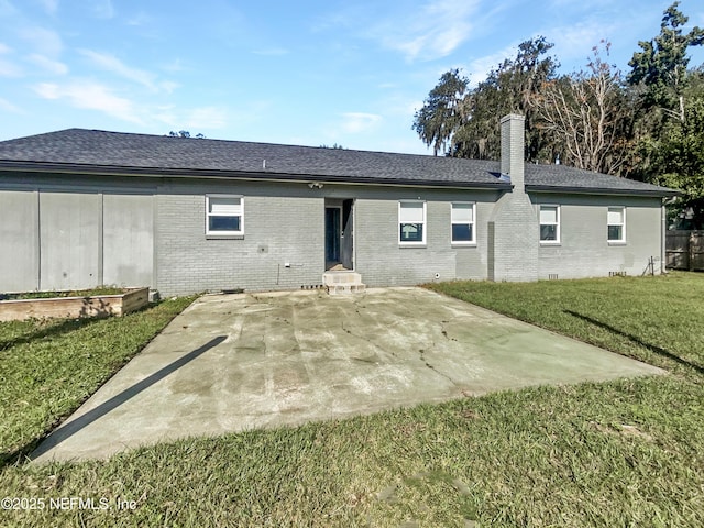 back of house with brick siding, a vegetable garden, a chimney, a lawn, and a patio area