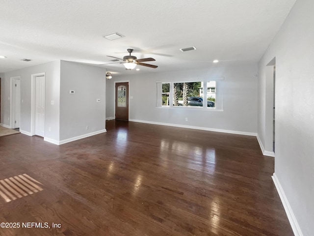 unfurnished living room with dark wood finished floors, visible vents, and baseboards