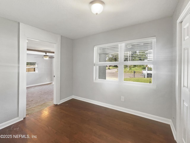 empty room with baseboards and dark wood-type flooring