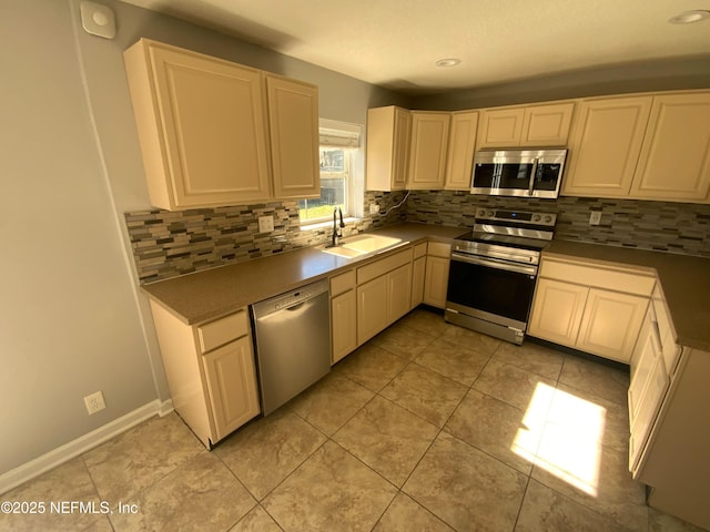 kitchen with appliances with stainless steel finishes, light tile patterned floors, a sink, and tasteful backsplash