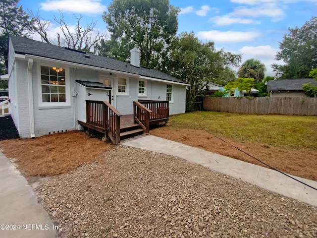 view of front of property featuring a front yard, fence, a wooden deck, a chimney, and brick siding