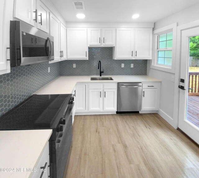 kitchen featuring stainless steel appliances, sink, decorative backsplash, light wood-type flooring, and white cabinets