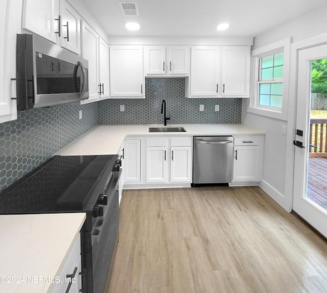 kitchen featuring visible vents, white cabinets, stainless steel appliances, and a sink