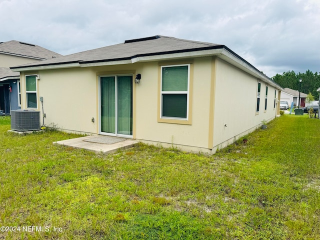 back of house with a lawn and central AC unit