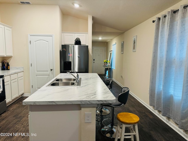 kitchen featuring stainless steel fridge, white cabinetry, sink, lofted ceiling, and a center island with sink