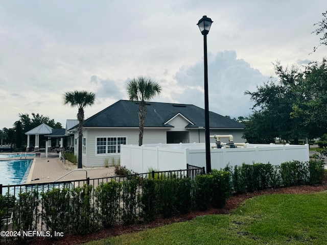 rear view of property with a fenced in pool, a lawn, and a patio