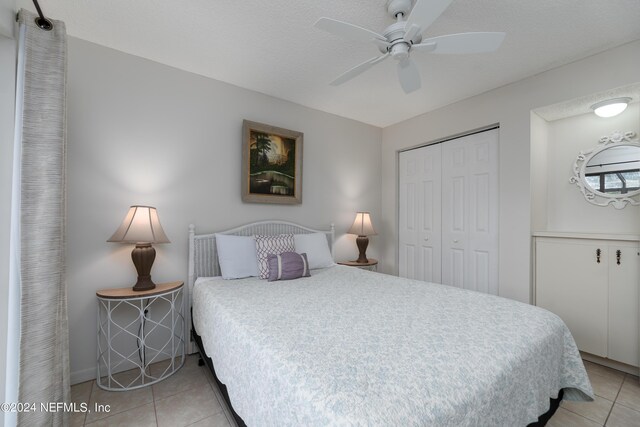 bedroom with a closet, ceiling fan, a textured ceiling, and light tile patterned flooring