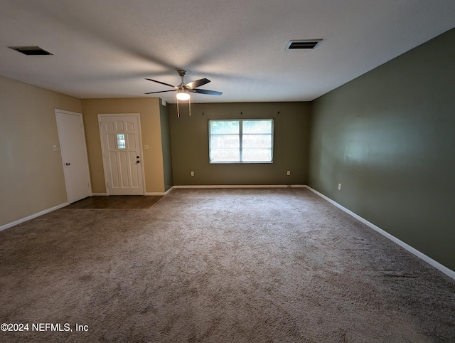 carpeted empty room with ceiling fan and a textured ceiling