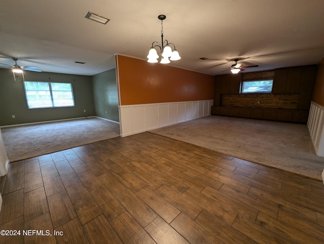 unfurnished living room with ceiling fan with notable chandelier and carpet flooring