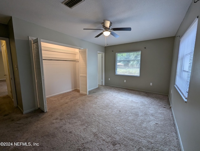 unfurnished bedroom with ceiling fan, a textured ceiling, a closet, and carpet flooring