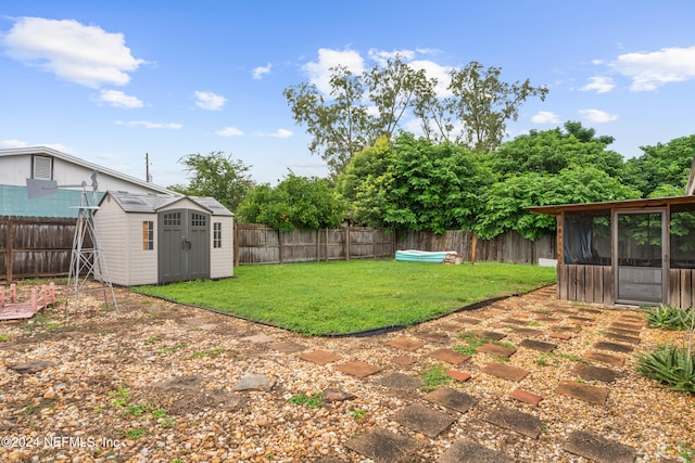 view of yard featuring a patio area, a sunroom, and a storage shed