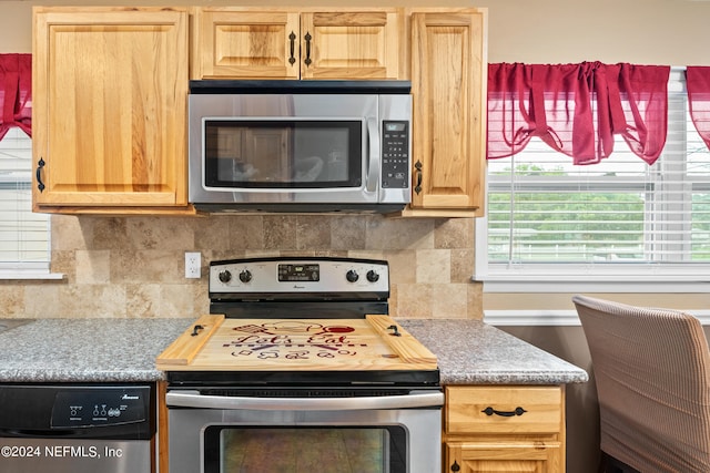 kitchen with stainless steel appliances, light brown cabinets, and backsplash