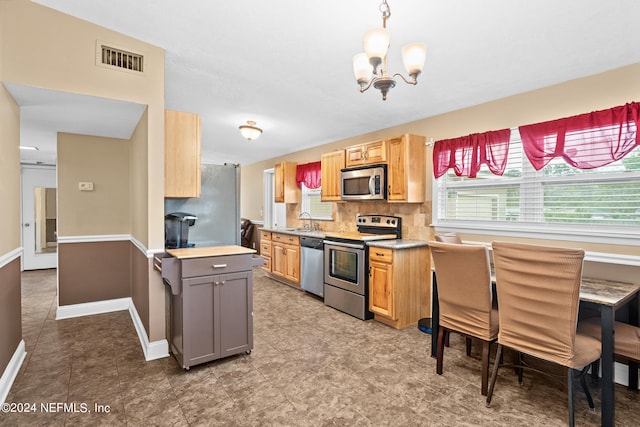 kitchen featuring gray cabinetry, decorative light fixtures, an inviting chandelier, tasteful backsplash, and stainless steel appliances