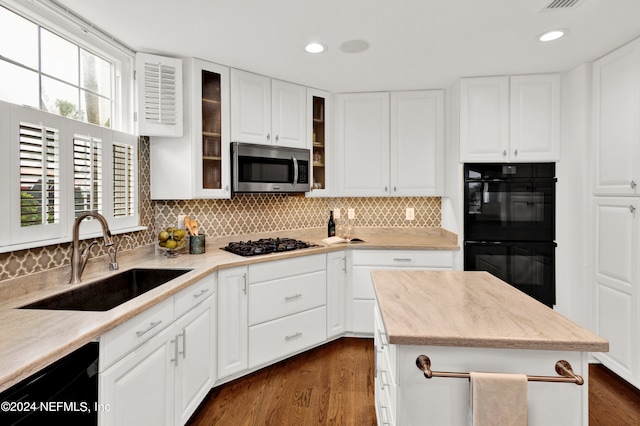 kitchen featuring decorative backsplash, white cabinetry, dark hardwood / wood-style flooring, black appliances, and sink