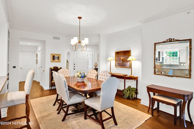 dining area with wood-type flooring, a chandelier, and crown molding