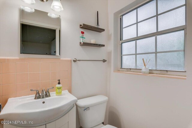 bathroom with toilet, decorative backsplash, and sink