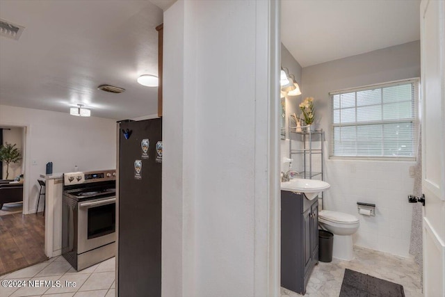 interior space with tile walls, toilet, hardwood / wood-style flooring, and vanity