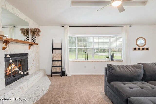 living room featuring ceiling fan, a fireplace, and light carpet