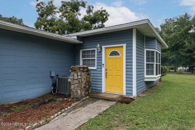 entrance to property featuring central AC unit and a yard