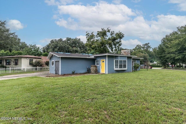 view of front facade with concrete driveway, a front yard, and fence