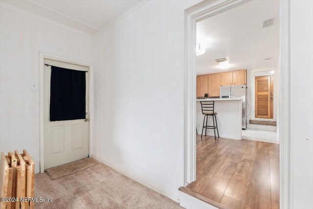 corridor featuring crown molding, radiator, and light wood-type flooring