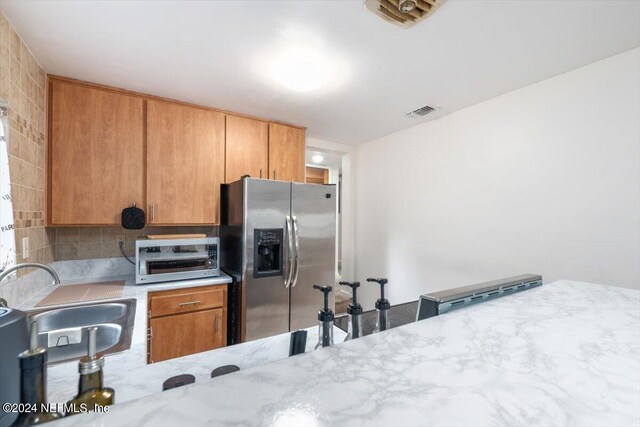 kitchen featuring sink, stainless steel fridge, and backsplash