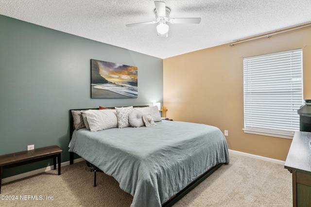 bedroom with light carpet, ceiling fan, and a textured ceiling