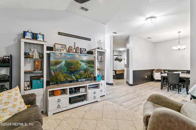 living room with a notable chandelier, light wood-type flooring, lofted ceiling, and a textured ceiling