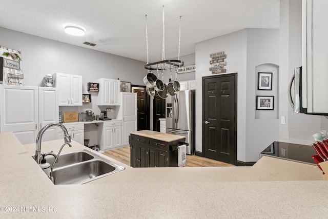 kitchen with white cabinetry, a kitchen island, stainless steel appliances, light wood-type flooring, and sink