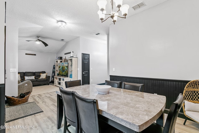 dining area featuring a textured ceiling, ceiling fan with notable chandelier, lofted ceiling, and light hardwood / wood-style flooring