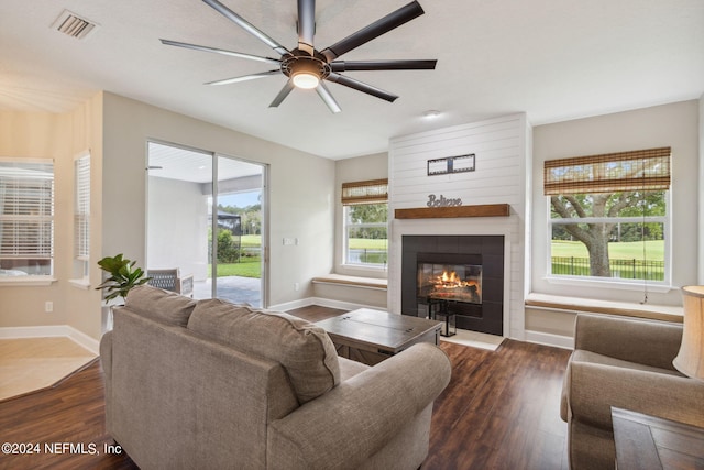 living room featuring dark hardwood / wood-style flooring, ceiling fan, and a tiled fireplace