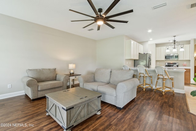 living room with ceiling fan with notable chandelier and dark wood-type flooring