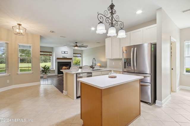 kitchen featuring white cabinetry, stainless steel appliances, kitchen peninsula, pendant lighting, and a kitchen island