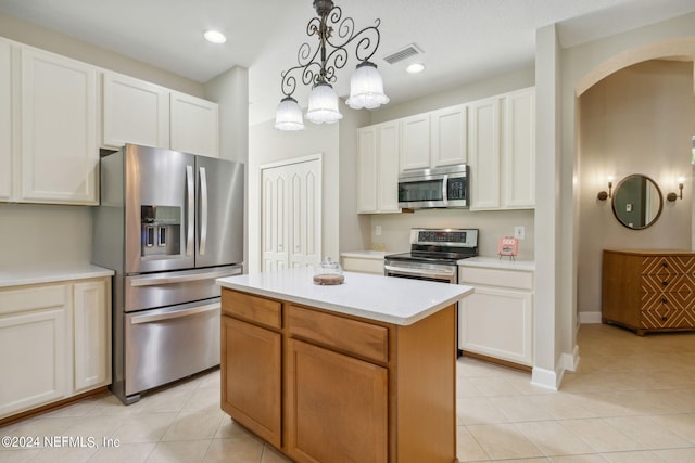 kitchen with white cabinets, a center island, stainless steel appliances, and hanging light fixtures