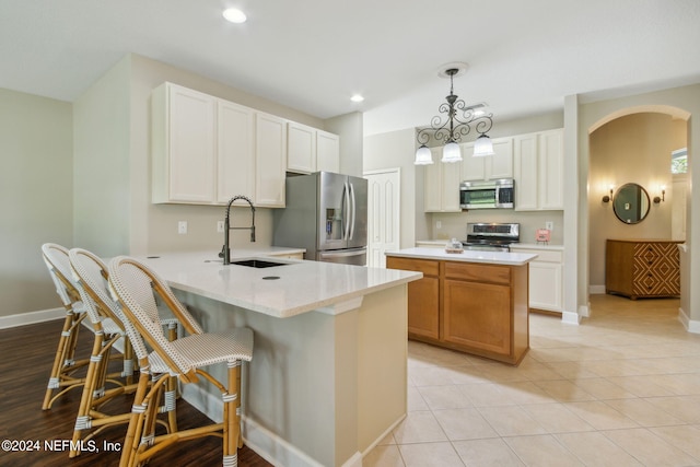 kitchen with sink, hanging light fixtures, kitchen peninsula, white cabinets, and appliances with stainless steel finishes