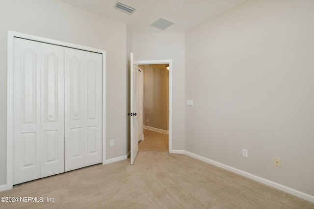 unfurnished bedroom featuring light carpet and a closet