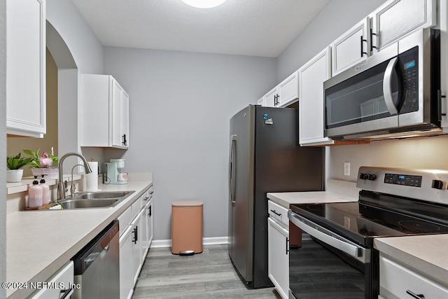 kitchen with white cabinets, stainless steel appliances, light hardwood / wood-style floors, and sink