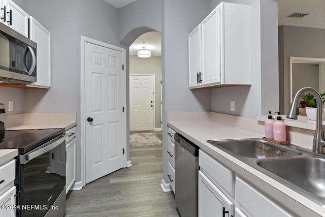 kitchen with light hardwood / wood-style flooring, sink, appliances with stainless steel finishes, and white cabinetry