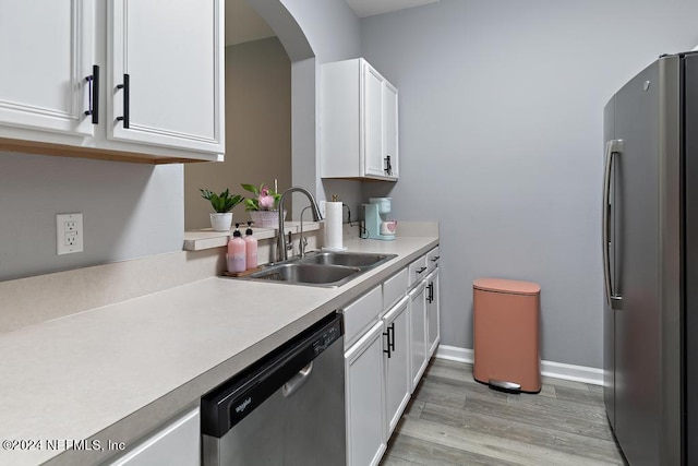 kitchen with light hardwood / wood-style flooring, sink, appliances with stainless steel finishes, and white cabinets